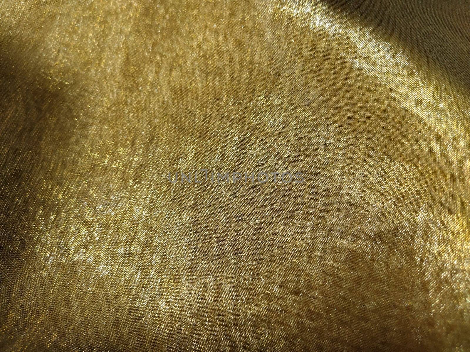 Beautiful gold fabric. Organza in yellow, orange, beige and brown shades. Pleats in the fabric. Shiny gradient under the light. Folded silky tulle. Transparent curtain material.