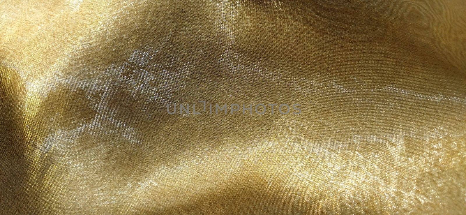 Beautiful gold fabric. Organza in yellow, orange, beige and brown shades. Pleats in the fabric. Shiny gradient under the light. Folded silky tulle. Transparent curtain material.