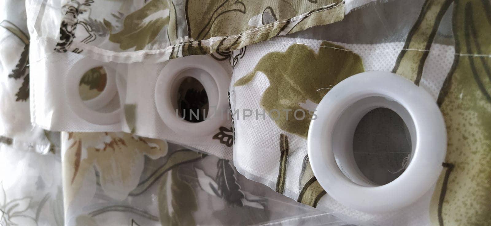 Plastic rings for attaching the fabric to the curtain rod. White plastic organza tulle eyelets. Light curtain in beige, brown or orange colors. White non-woven fabric. Finished textile edge. Interior element