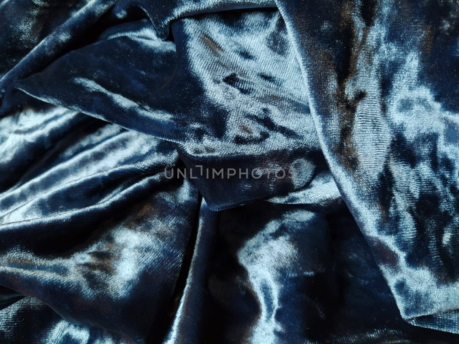 Velvet velor cloth background with glowing light and dark shadows. Background for theater and fashion design themes. Nice blue fabric with overflow.