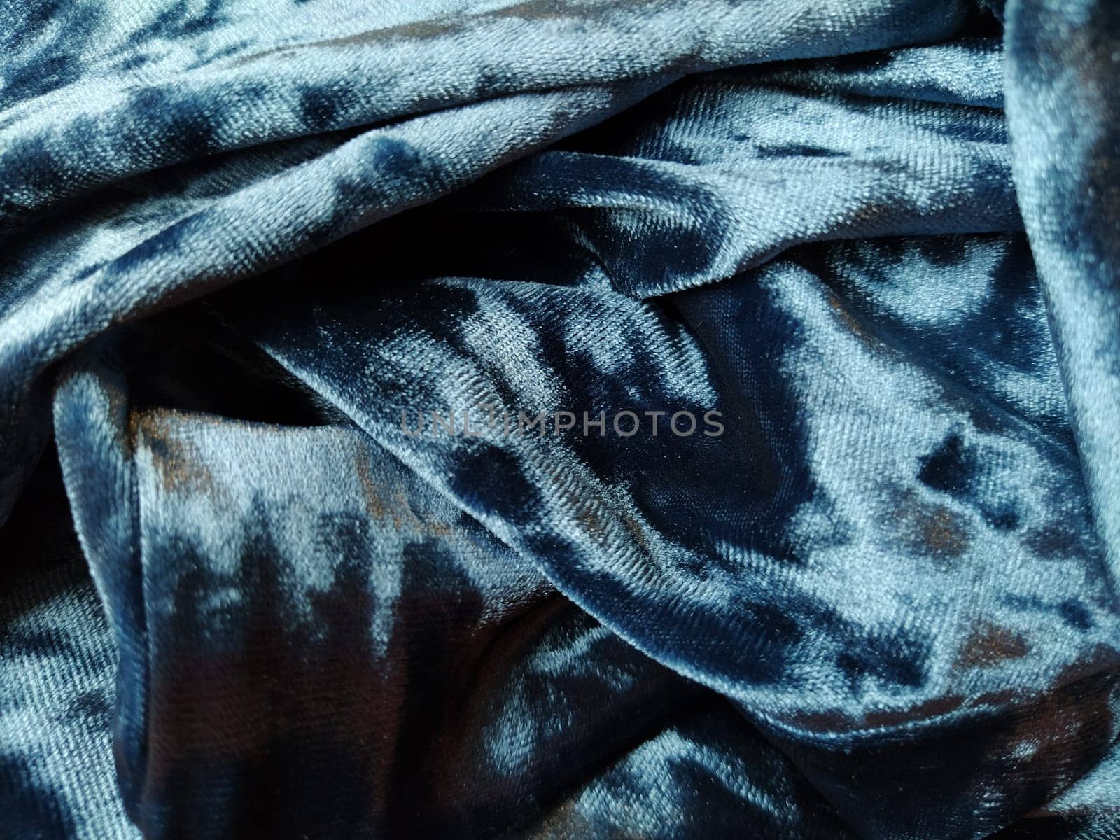 Velvet velor cloth background with glowing light and dark shadows. Background for theater and fashion design themes. Nice blue fabric with overflow.