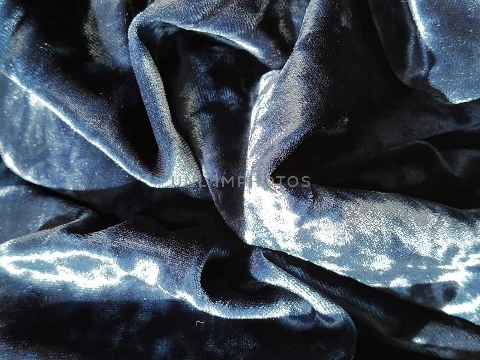 Velvet velor cloth background with glowing light and dark shadows. Background for theater and fashion design themes. Nice blue fabric with overflow.