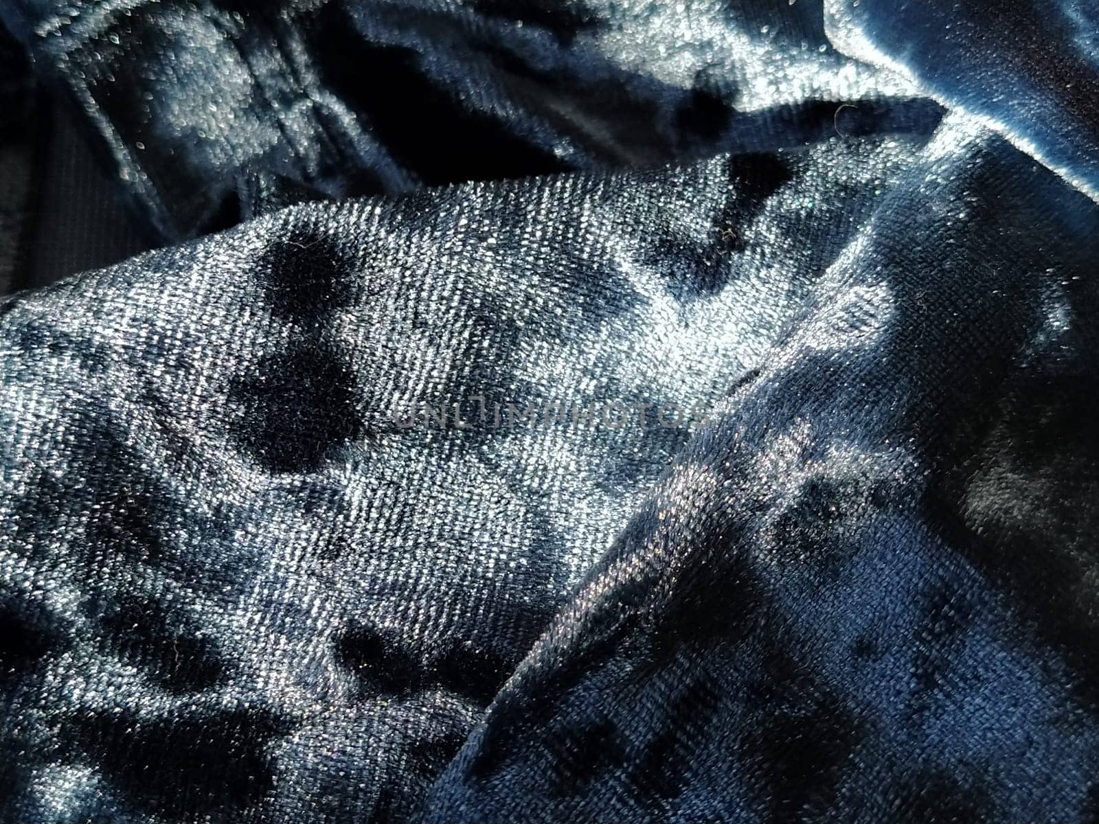 Velvet velor cloth background with glowing light and dark shadows. Background for theater and fashion design themes. Nice blue fabric with overflow.