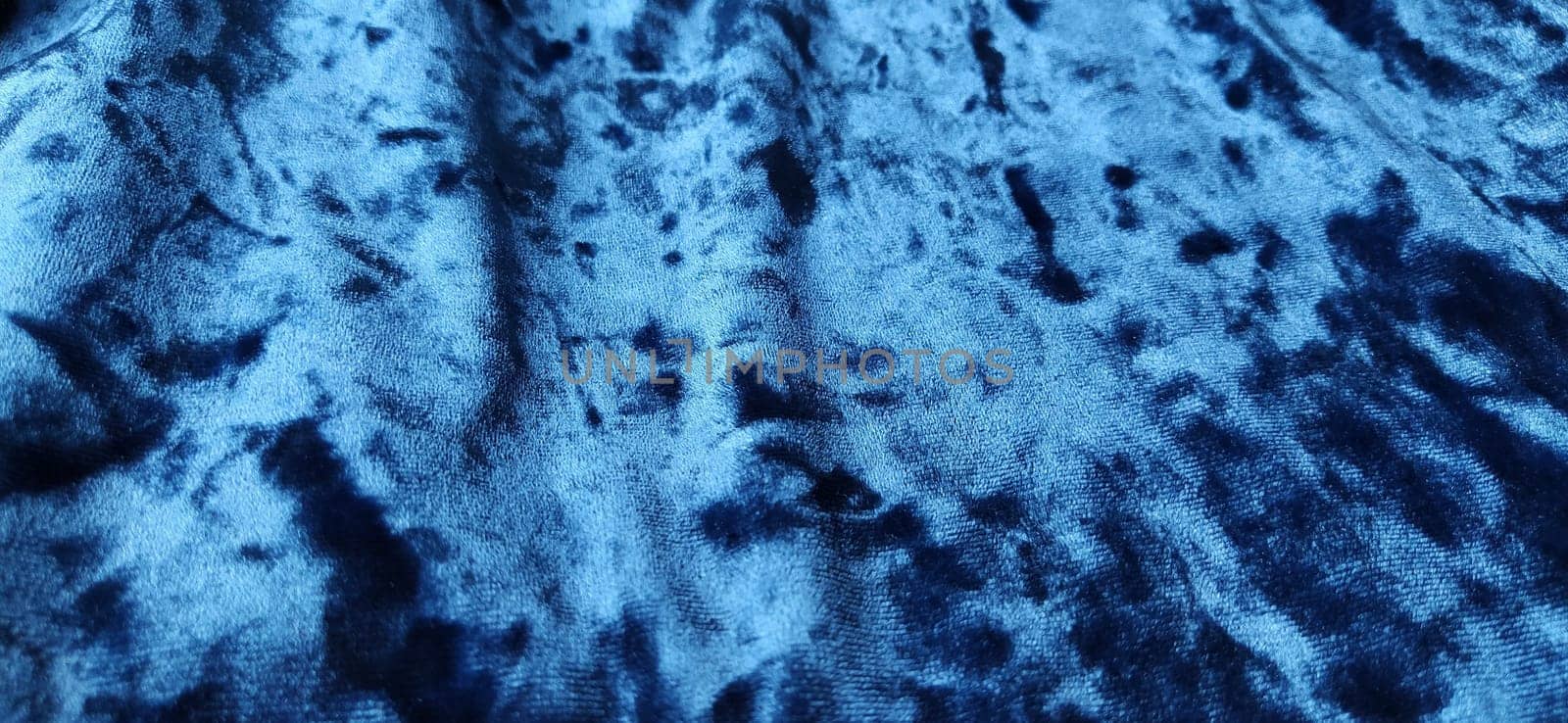 Velvet velor cloth background with glowing light and dark shadows. Background for theater and fashion design themes. Nice blue fabric with overflow.