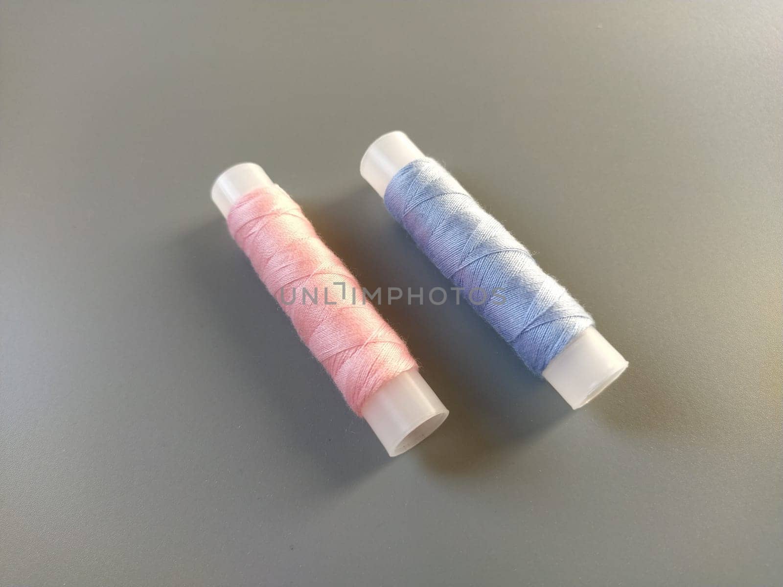 Spools of pink and blue thread on a gray background. Textile industry.