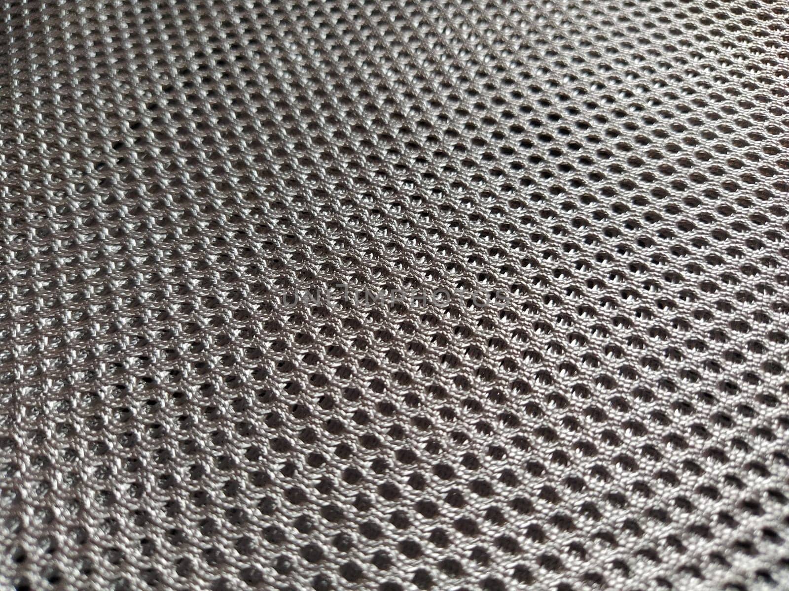 Abstract black nylon synthetic fabric. Gray artificial fabric mesh, resistant to pollution. Fragment of a child car seat close-up. Soft focus.