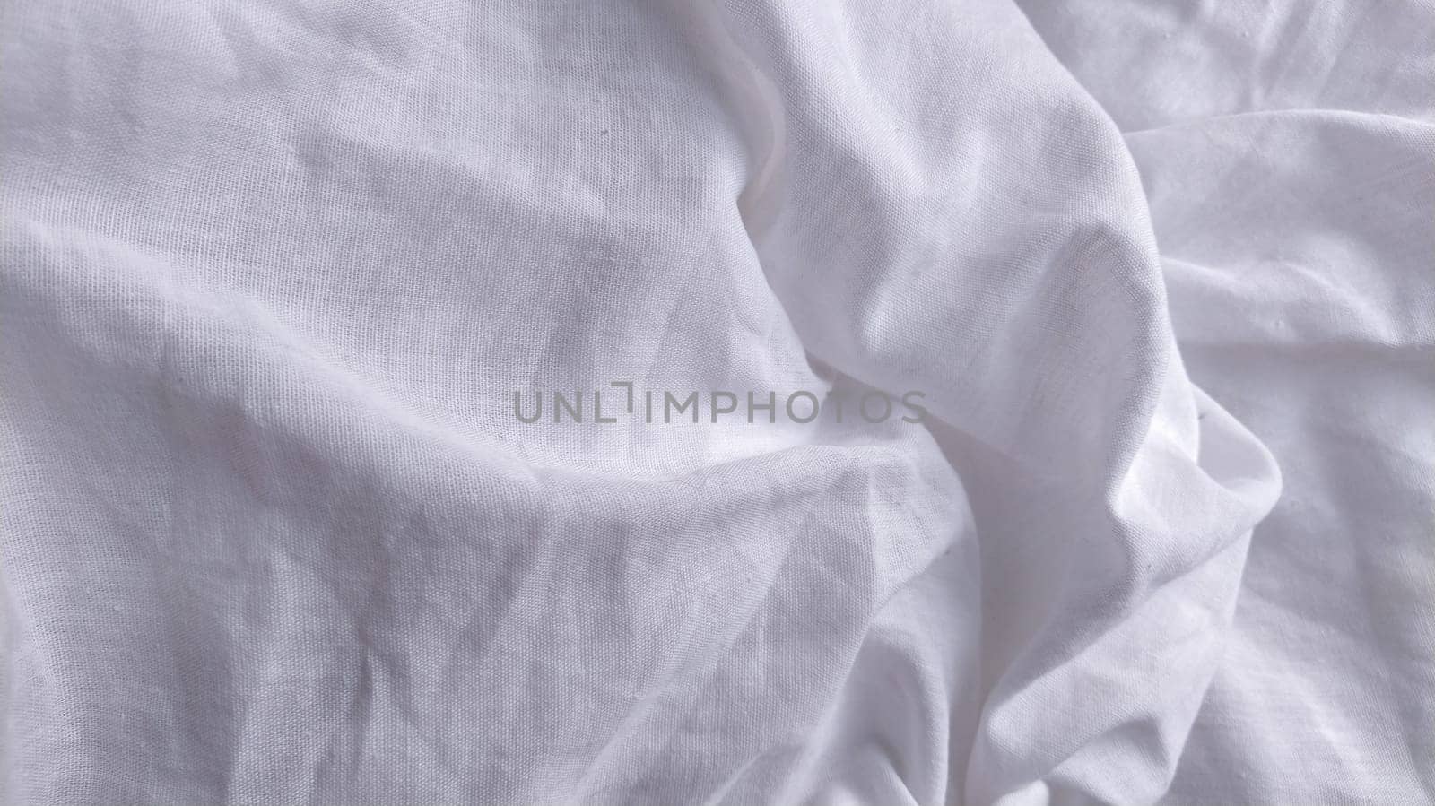 White cotton fabric, not ironed and crumpled in waves. White background. Tablecloth or sheet