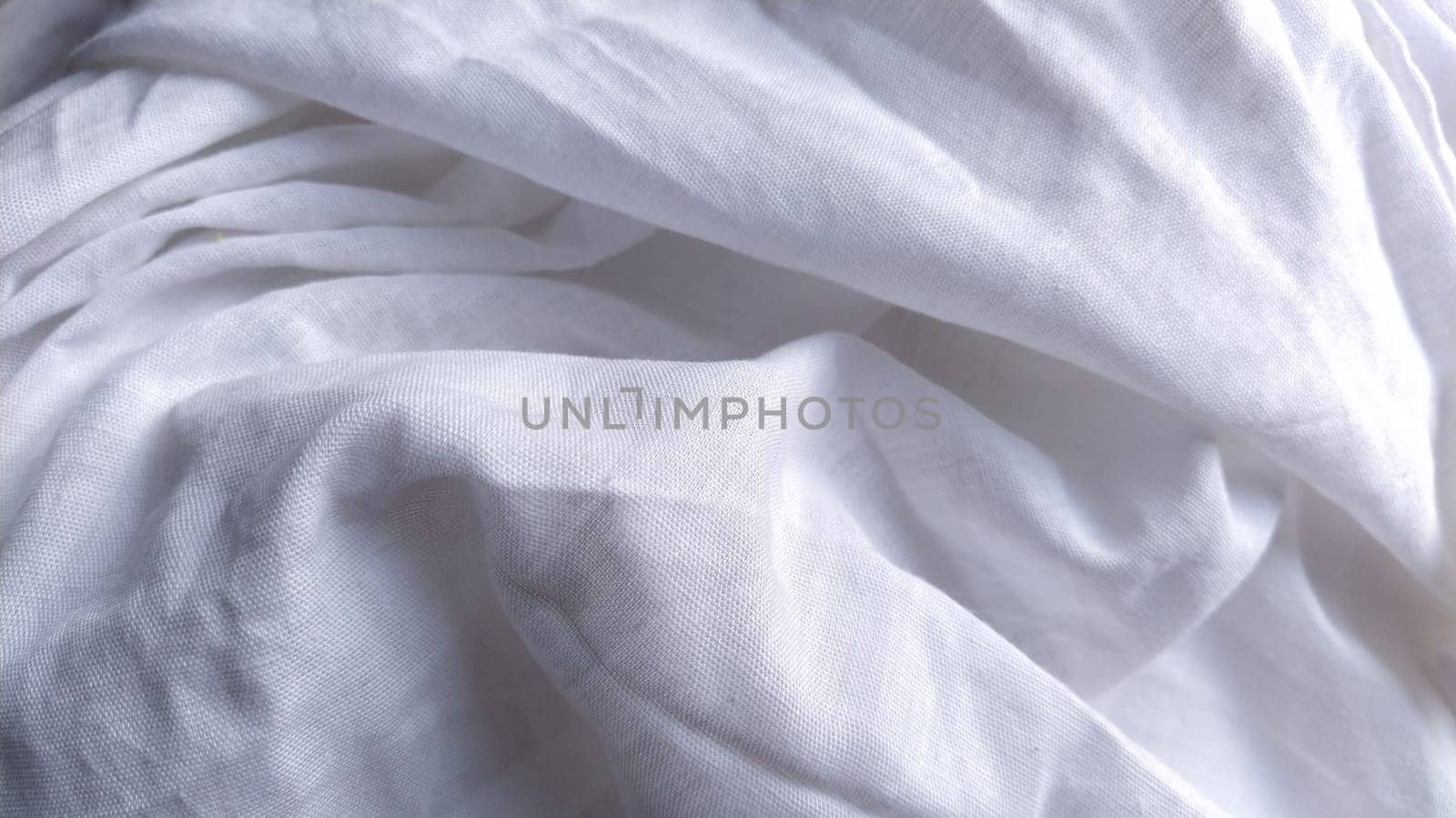 White cotton fabric, not ironed and crumpled in waves. White background. Tablecloth or sheet