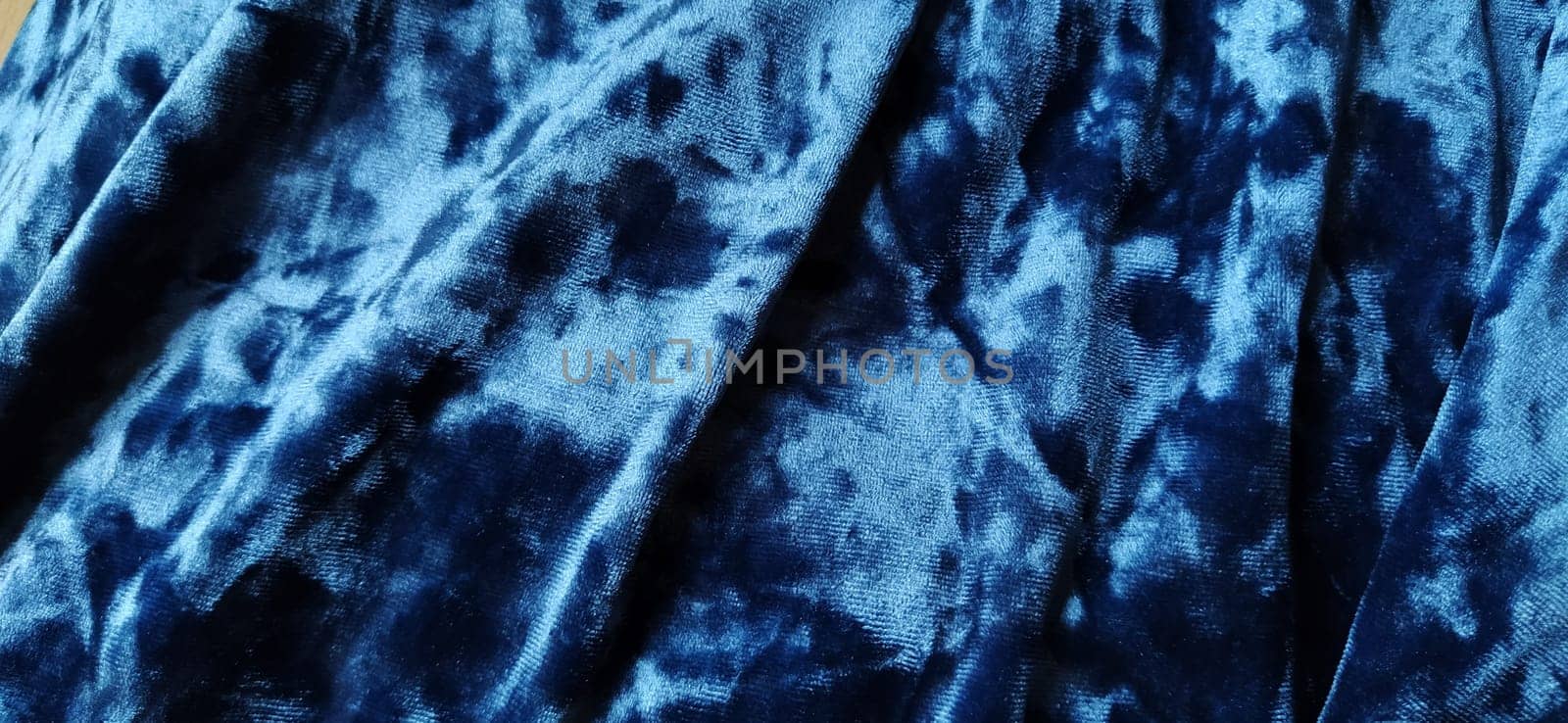 Velvet velor cloth background with glowing light and dark shadows. Background for theater and fashion design themes. Nice blue fabric with overflow.