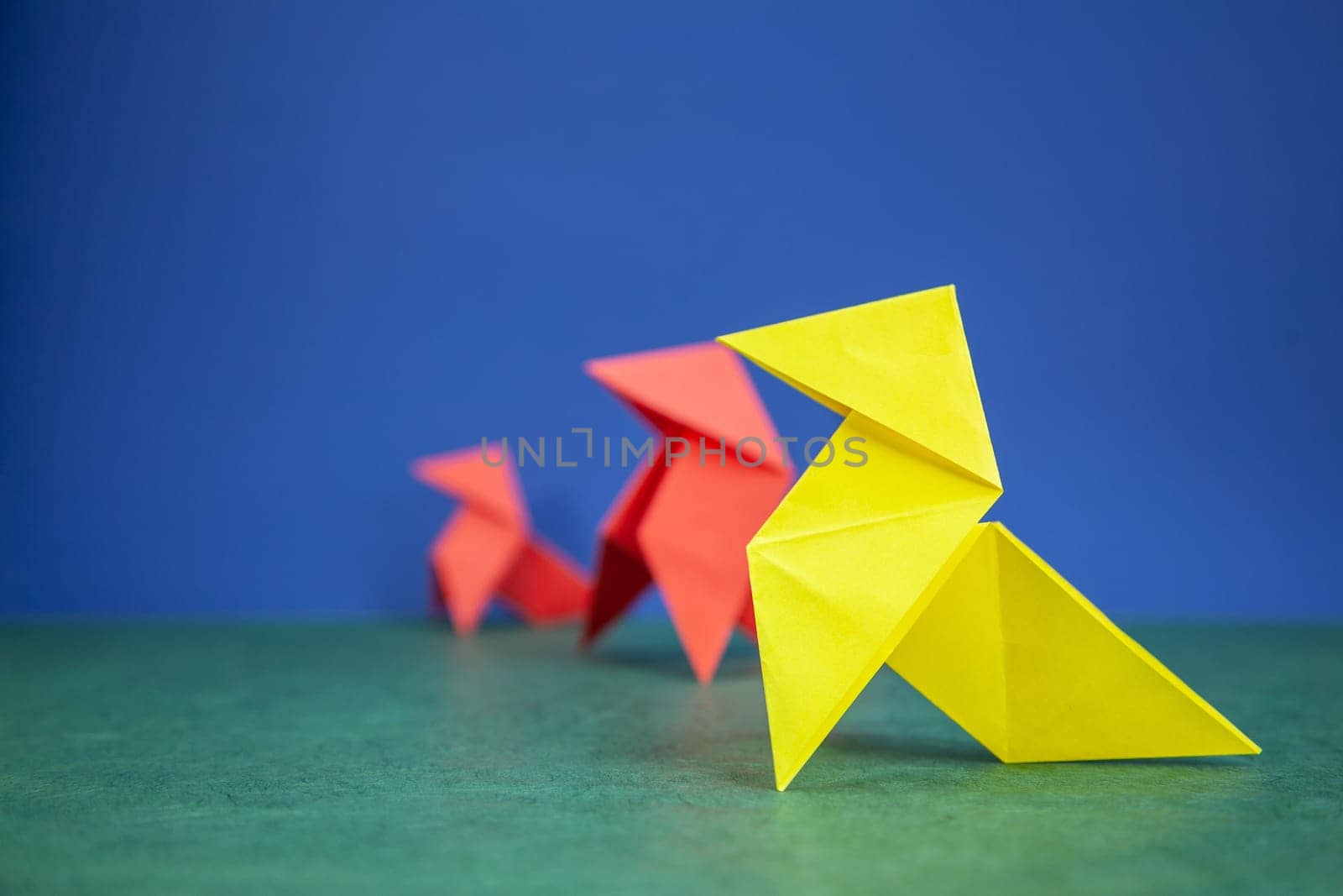 Paper hen origami over green and blue paper background