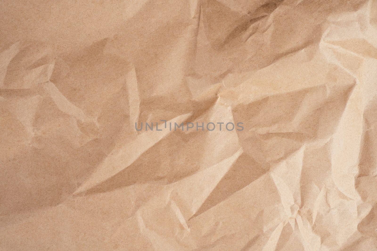 Background image of rough crumpled recycled textured kraft paper. Top view. Copy space