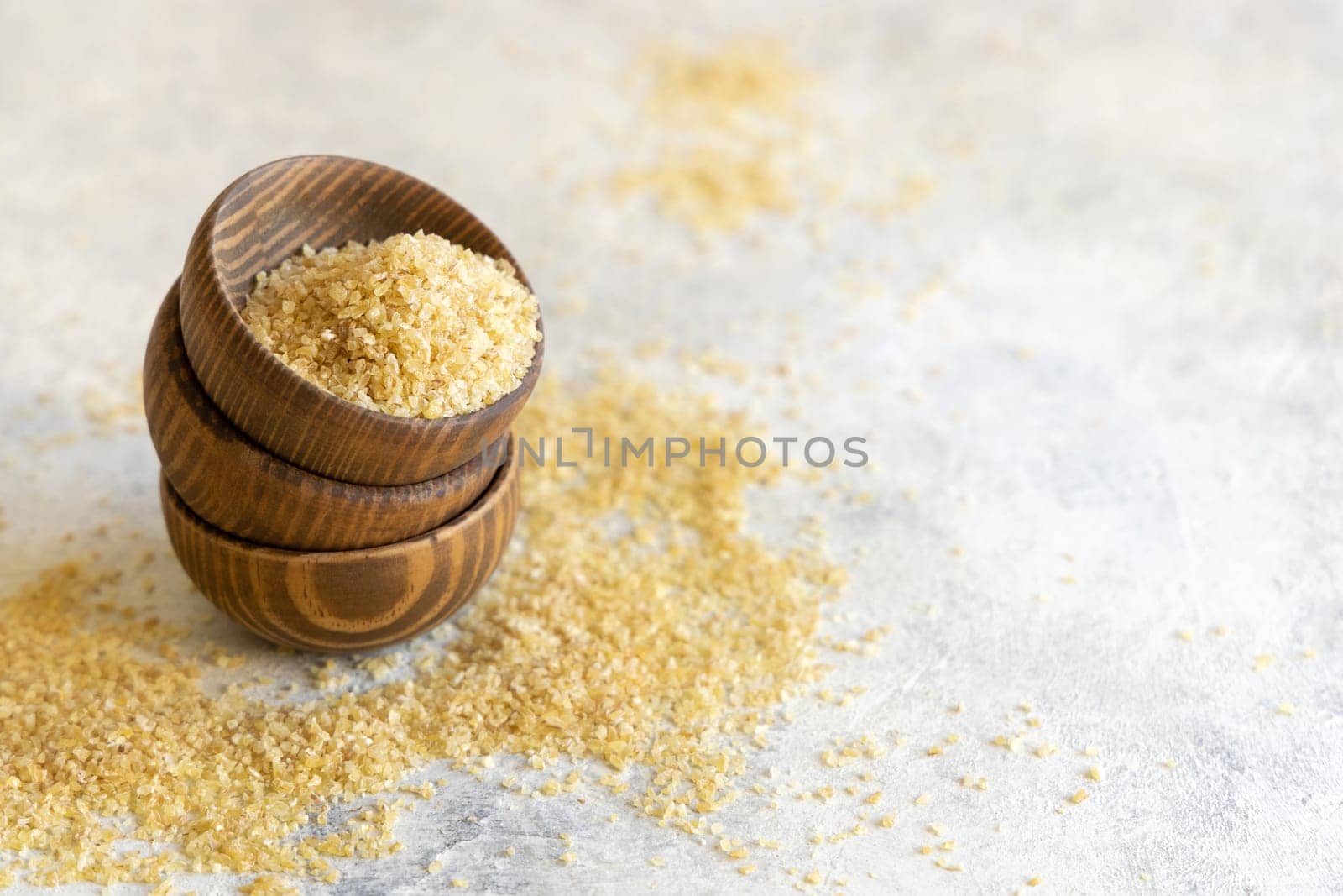 Wooden bowls with Dry uncooked bulgur wheat grain close up, copy space. Vegetarian and Vegan, Mediterranean and Middle Eastern cuisine. Healthy lifestyle