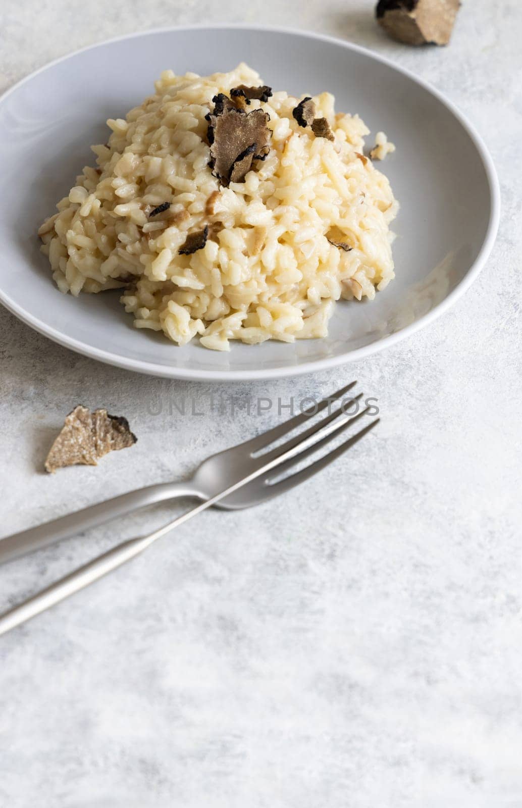 Risotto with wild porcini mushrooms and black truffles from Italy served in a plate close up on white table, copy space. Eating Italian gourmet cousine
