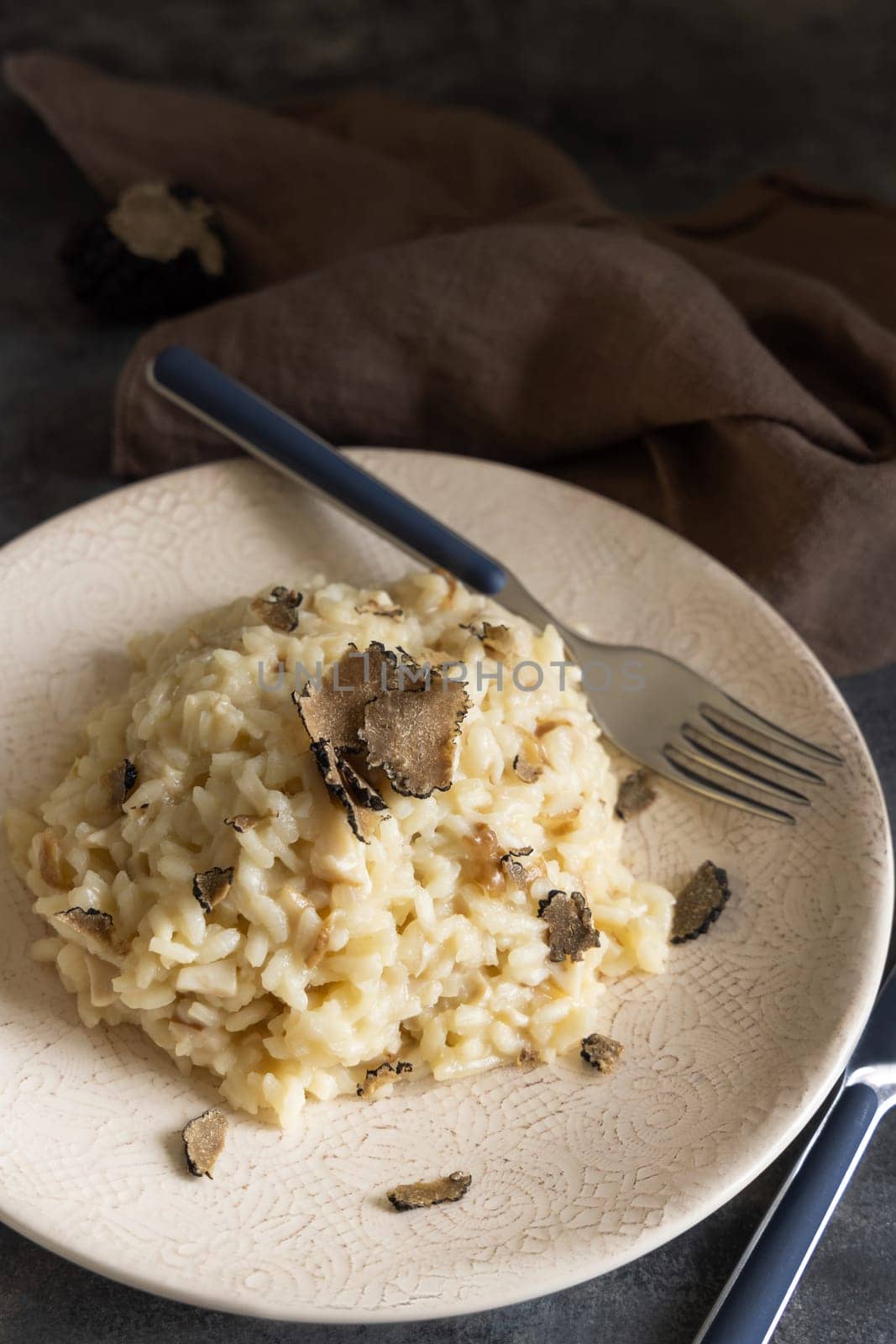 Risotto with wild porcini mushrooms and black truffles from Italy served in a plate close up on grey table, copy space. Eating Italian gourmet cousine