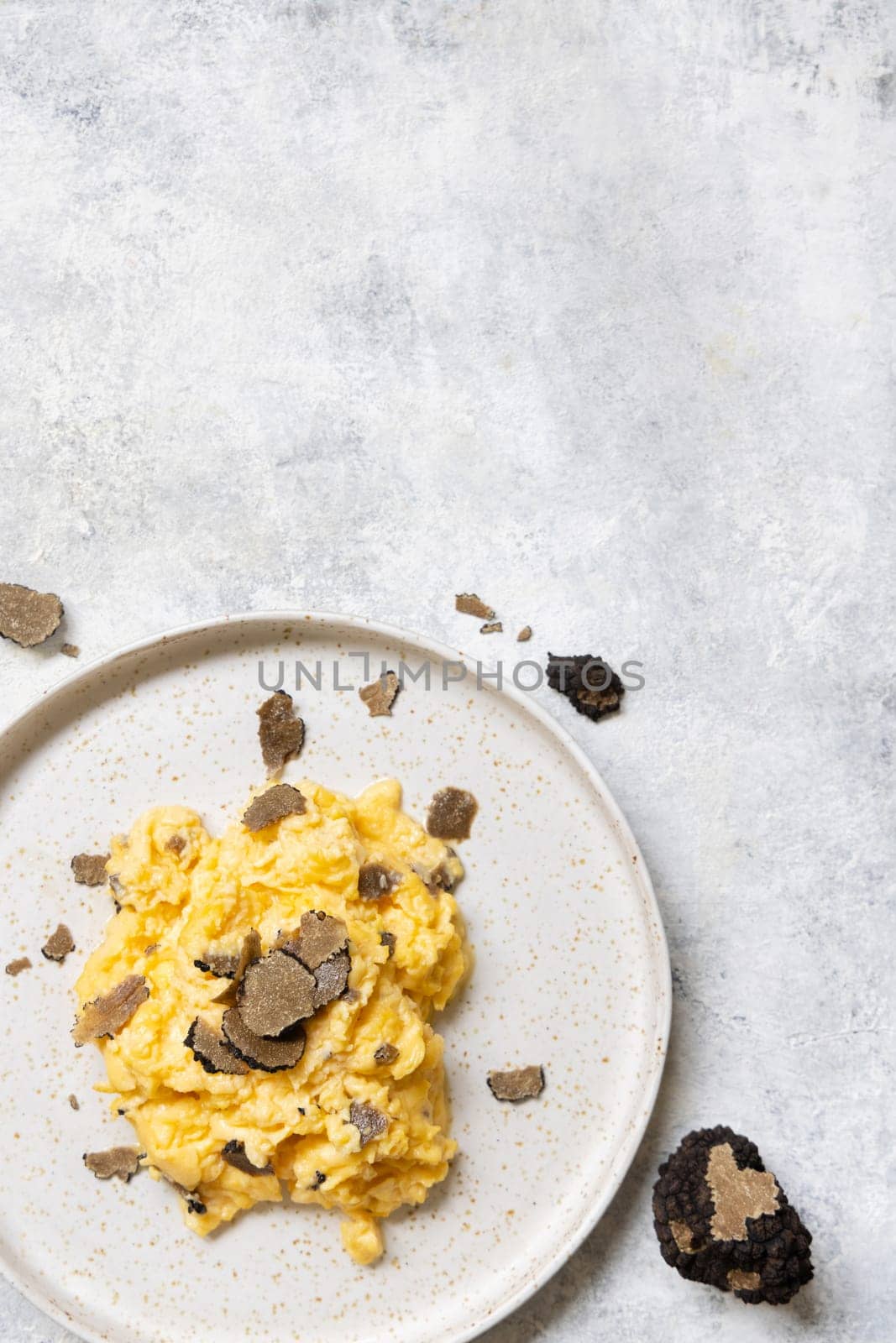 Scrambled eggs with sliced fresh black truffles from Italy served in a plate top view, copy space. Italian cousine, gourmet breakfast