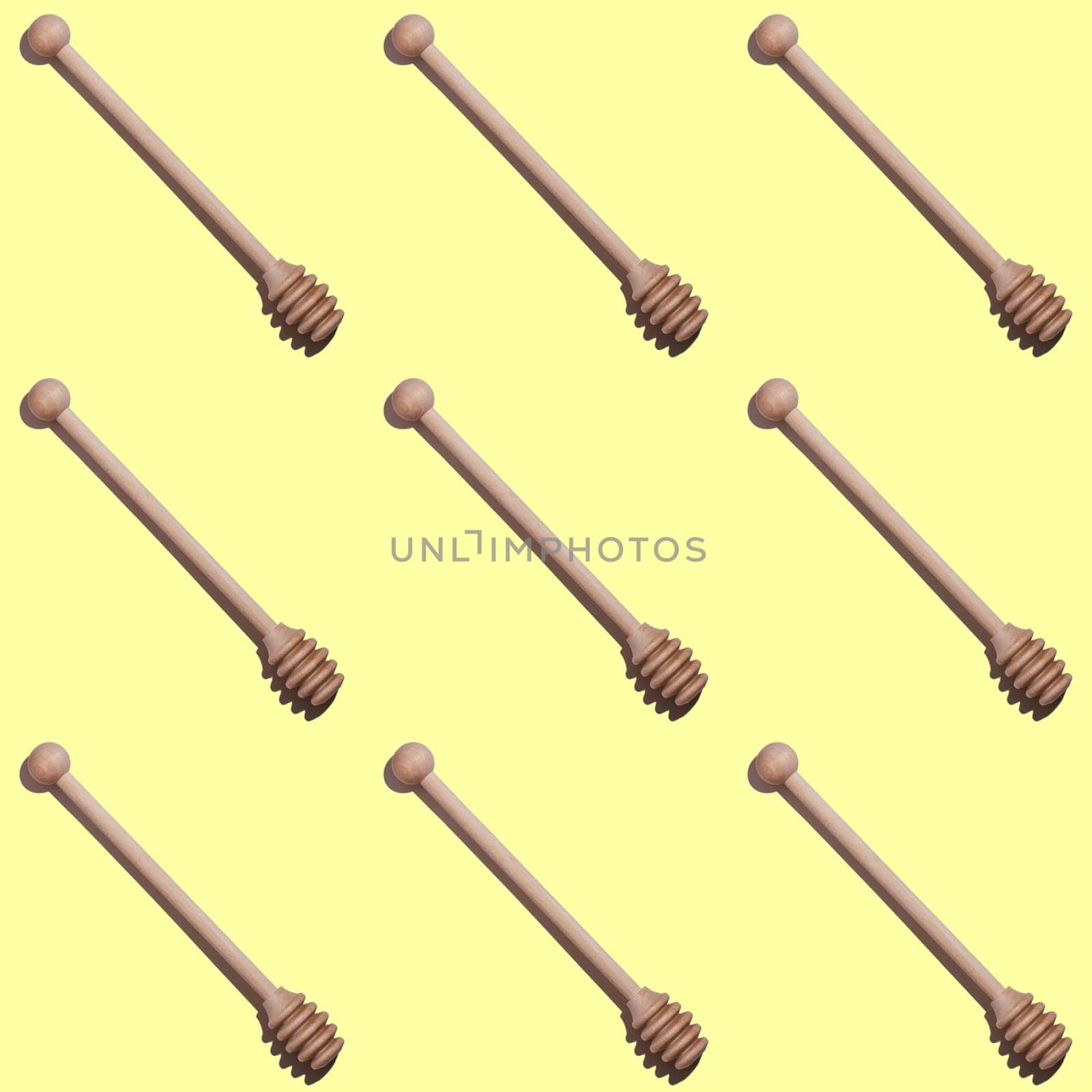 Seamless endless pattern of wooden honey spoons with hard shadows isolated on light yellow background. Top view