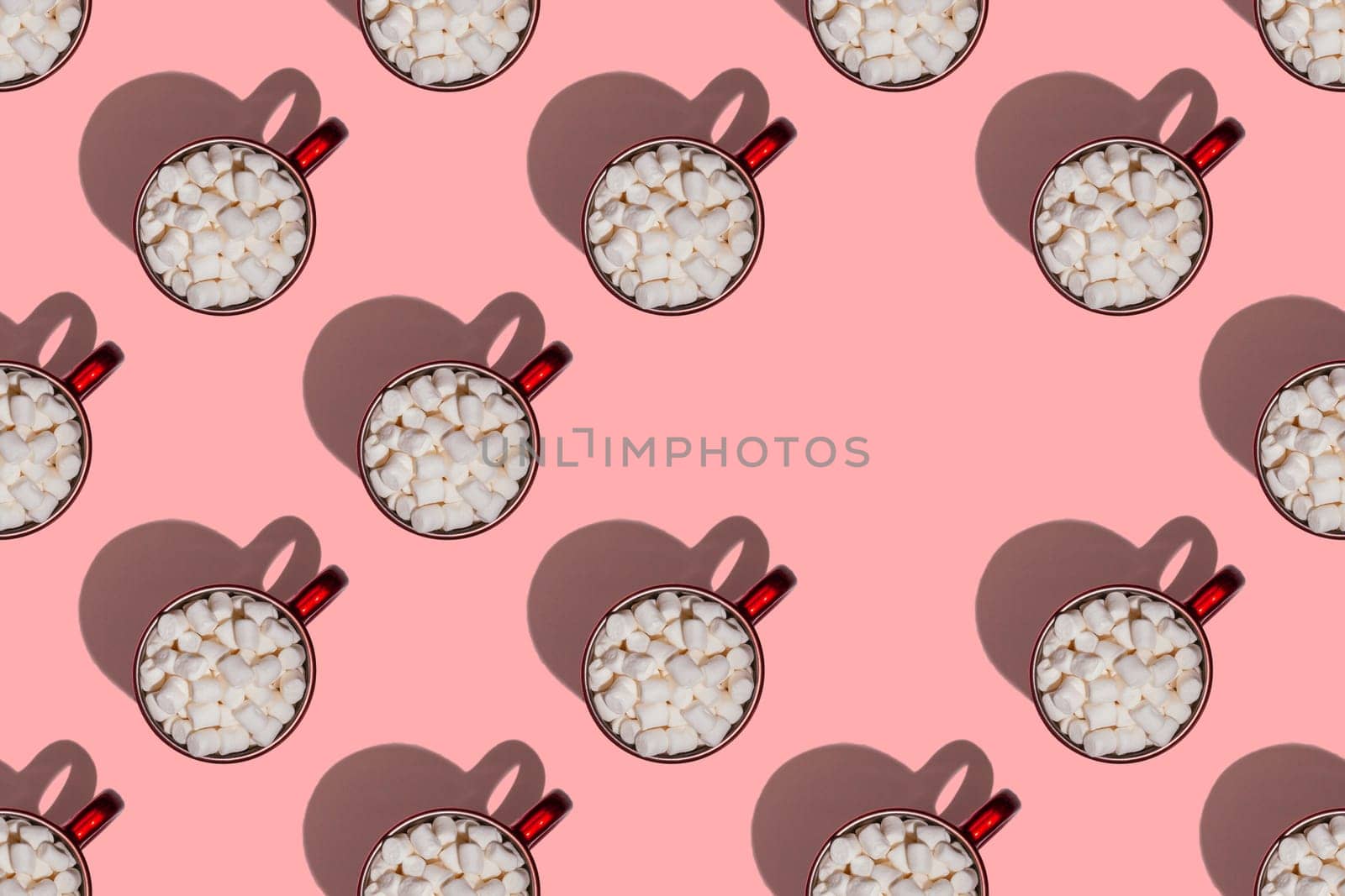 Pattern of red cups with hot chocolate, coffee or cocoa with marshmallows with hard shadows isolated on light pink background. Top view. Copy space