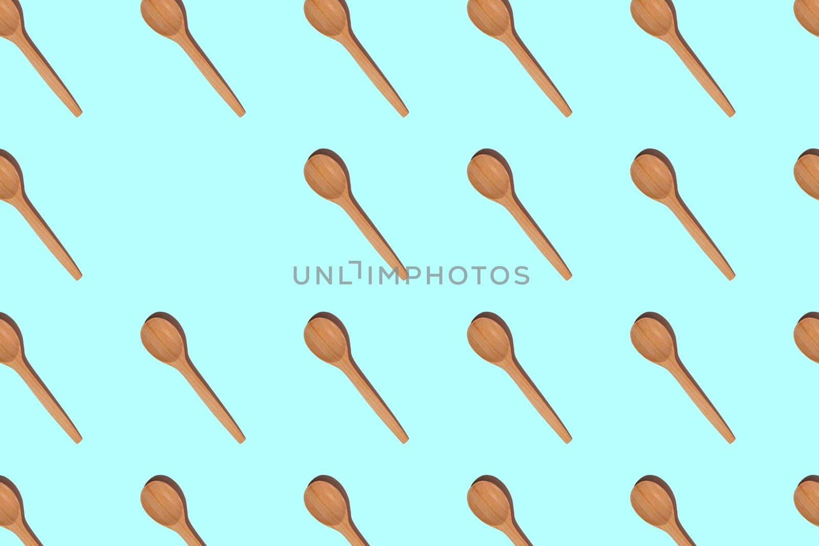 Pattern of wooden spoons with hard shadows isolated on light blue background. Copy space. Top view