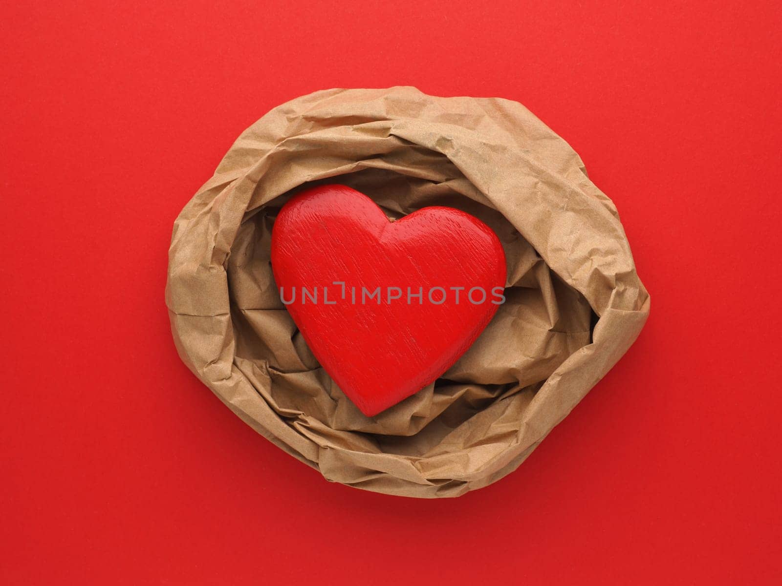 Wooden Heart decoration on crumpled beige paper and red paper background with space for text
