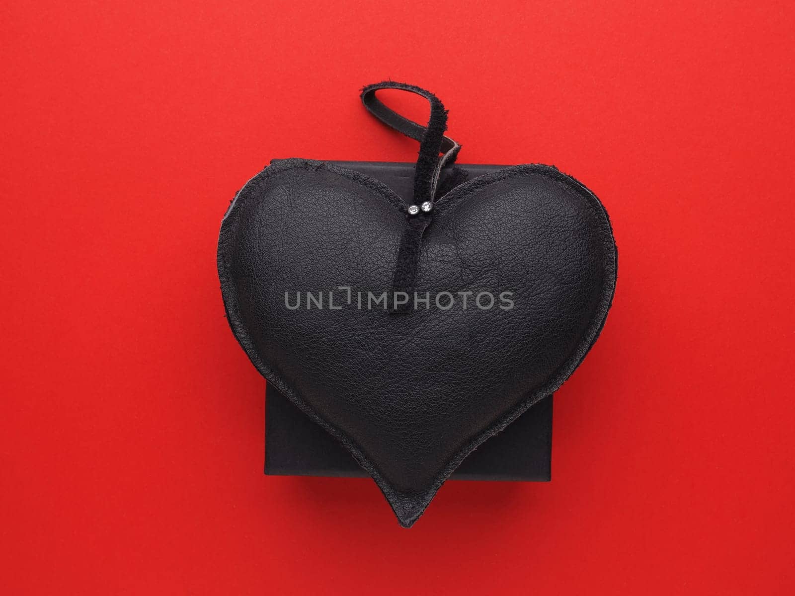 Black leather heart on a black gift box on red background, Valentines or Birthday, lovebackground