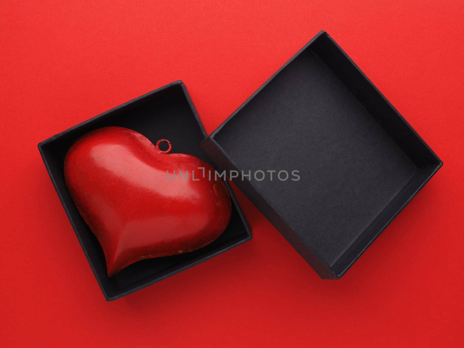 Red metal heart in a black gift box on red background, Valentines or Birthday concept