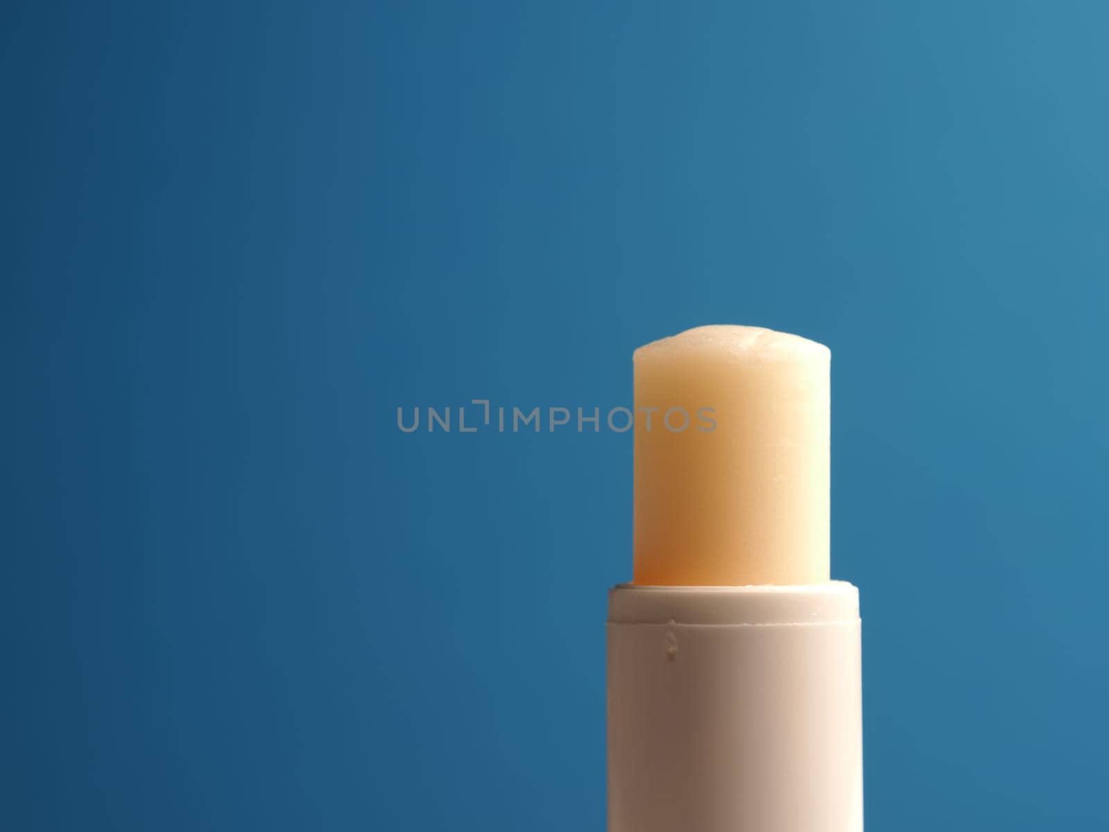 Close up of a lip balm stick on a blue background with space for your text or image, skin care or protection, hygiene concept