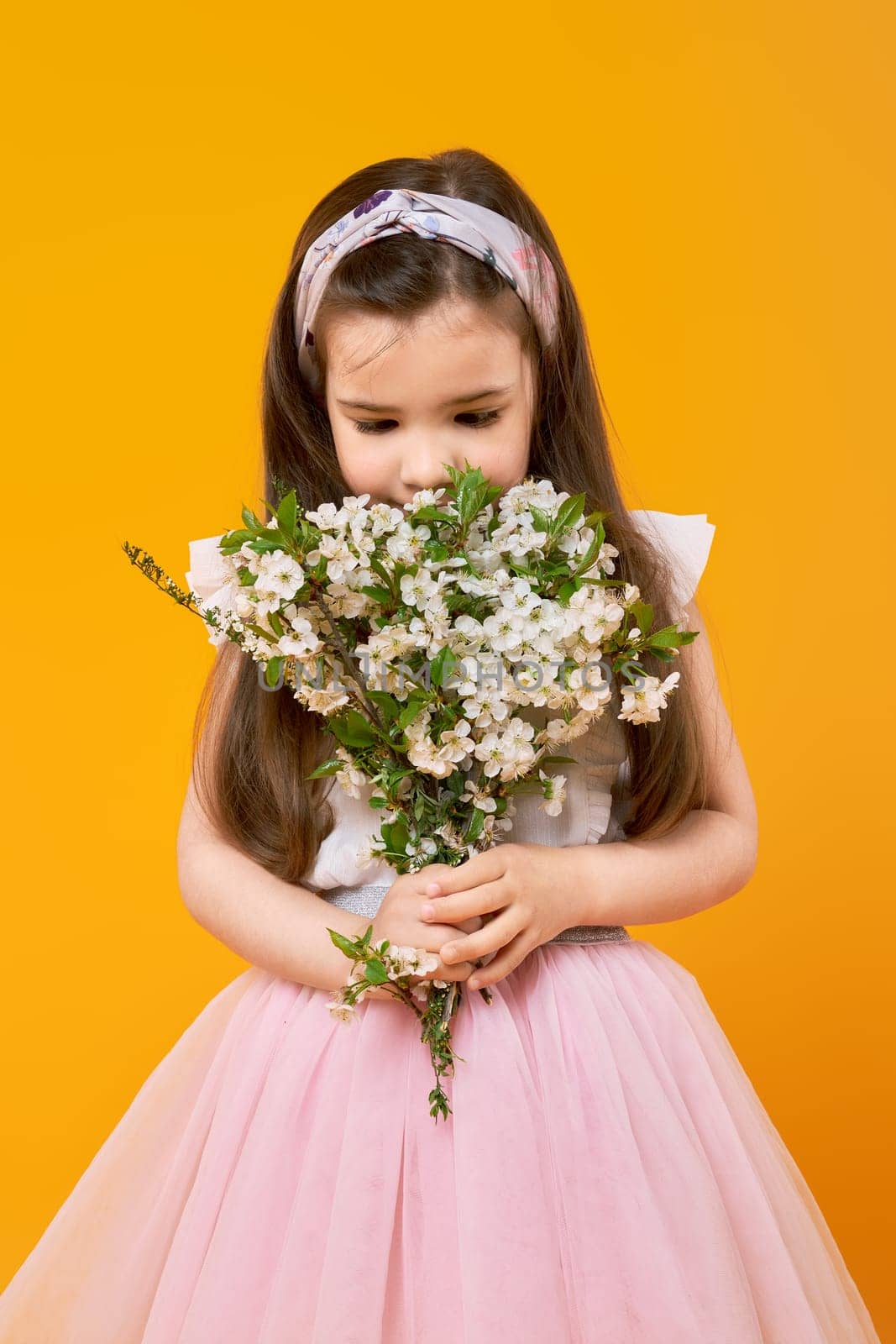 Cute little child sniffing the bouquet of spring flowers