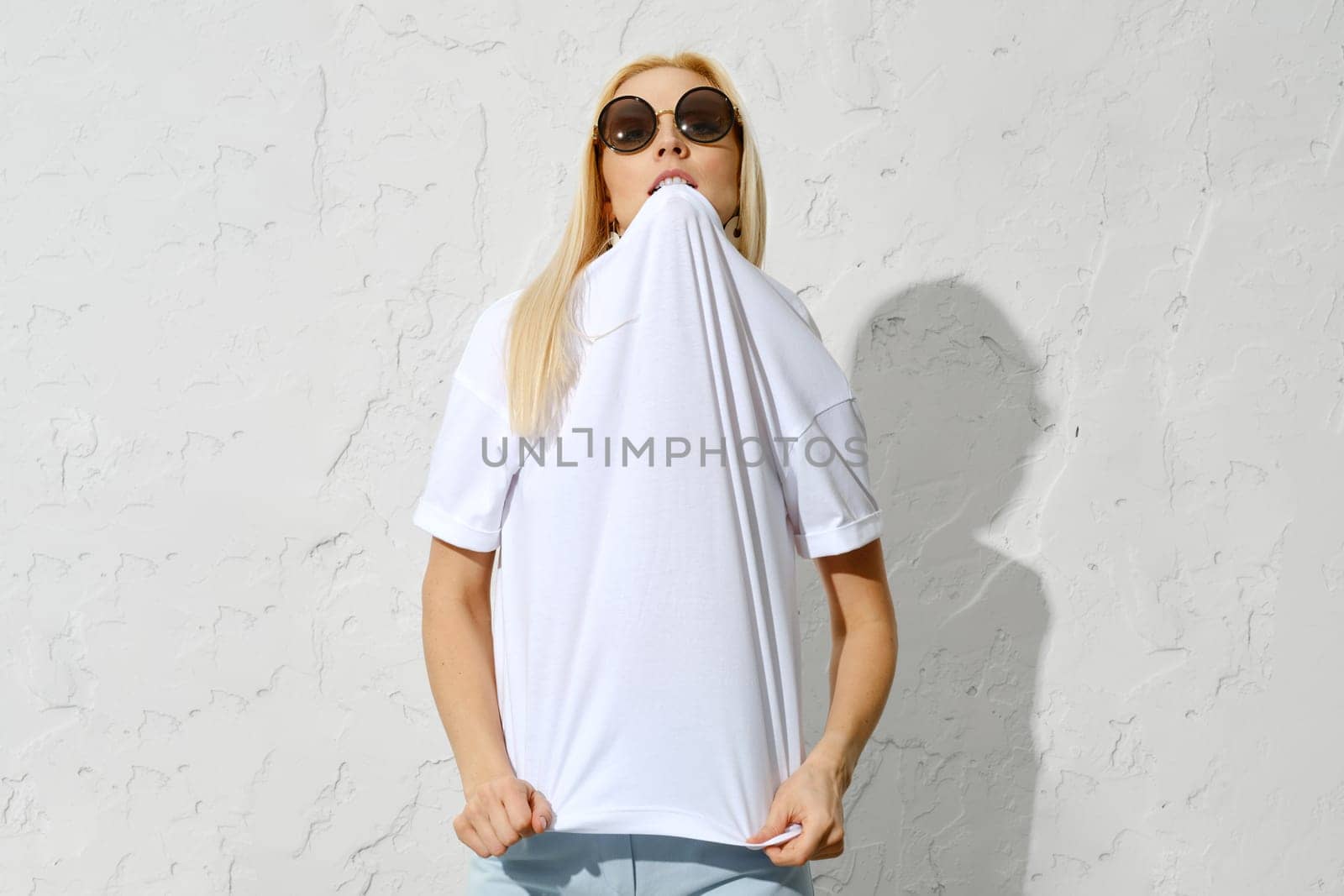 Playful blonde woman bites the collar of a t-shirt