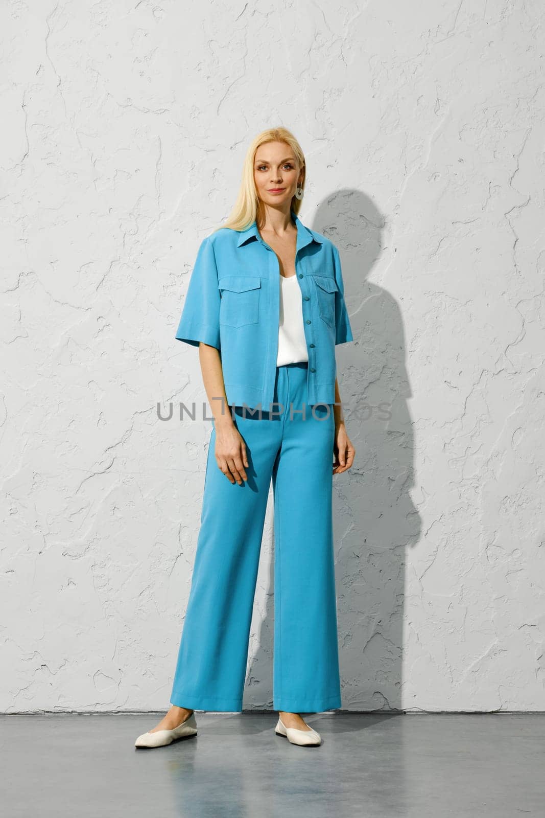 Fashion model in blue jacket and trousers posing under harsh light