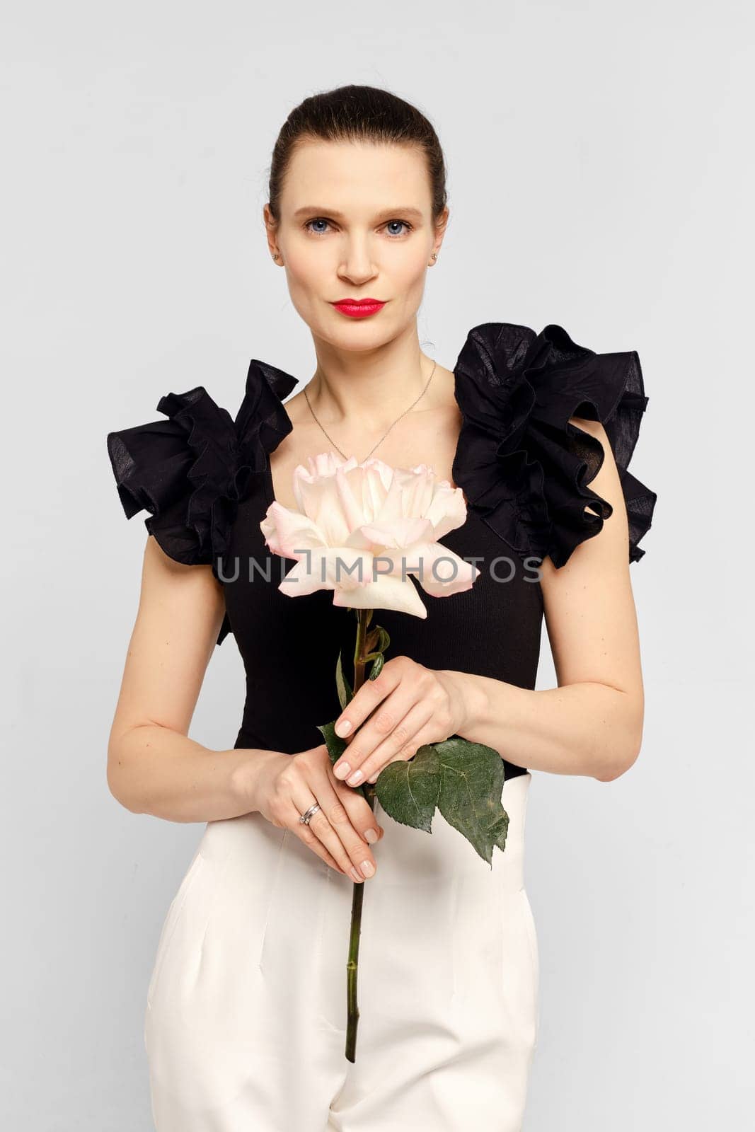 Gorgeous woman with healthy skin and natural makeup holds big rose in hand