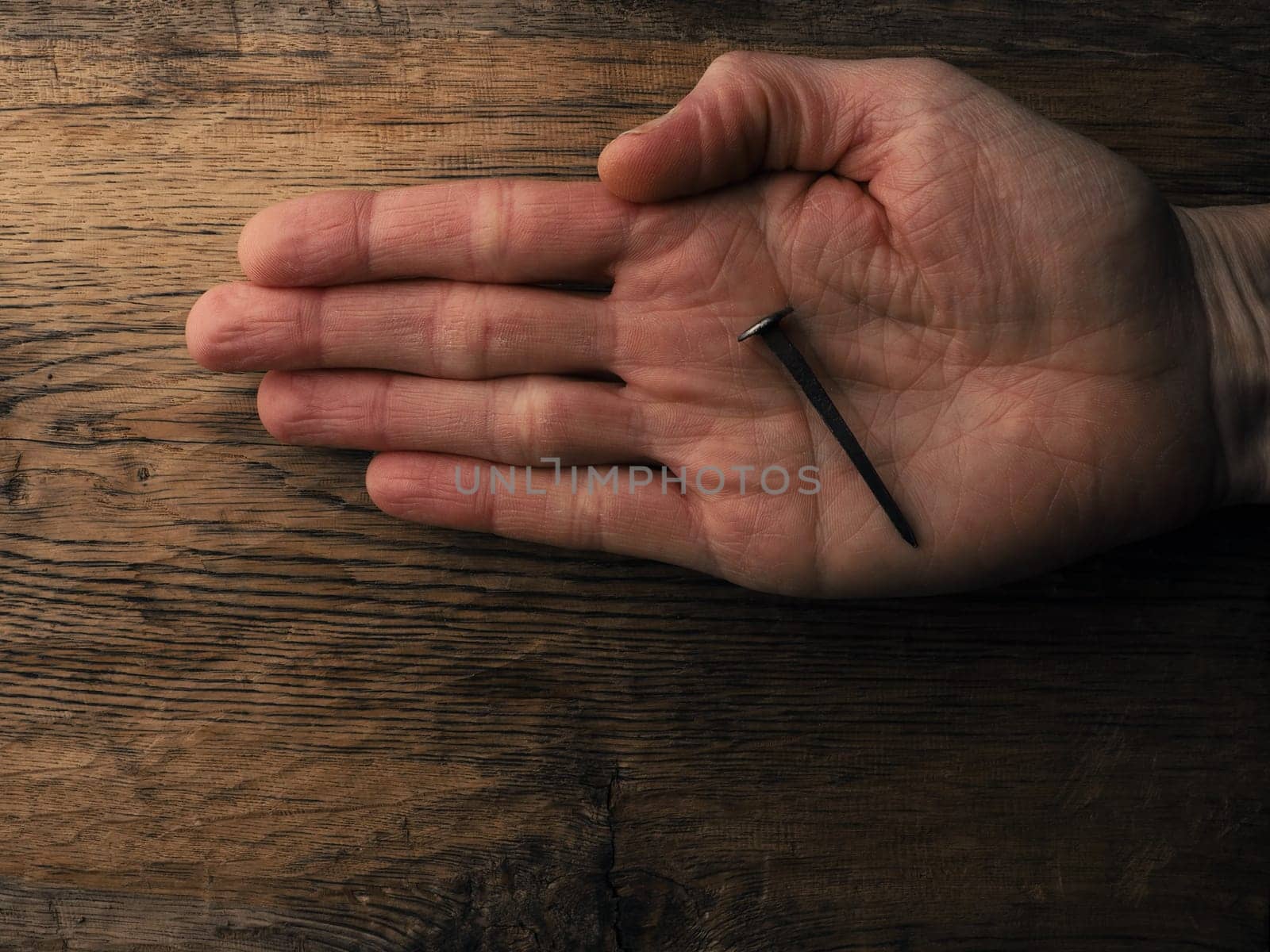 Hand with an old rusty nail symbolizes the crucifixion of Jesus. Easter concept with text free space