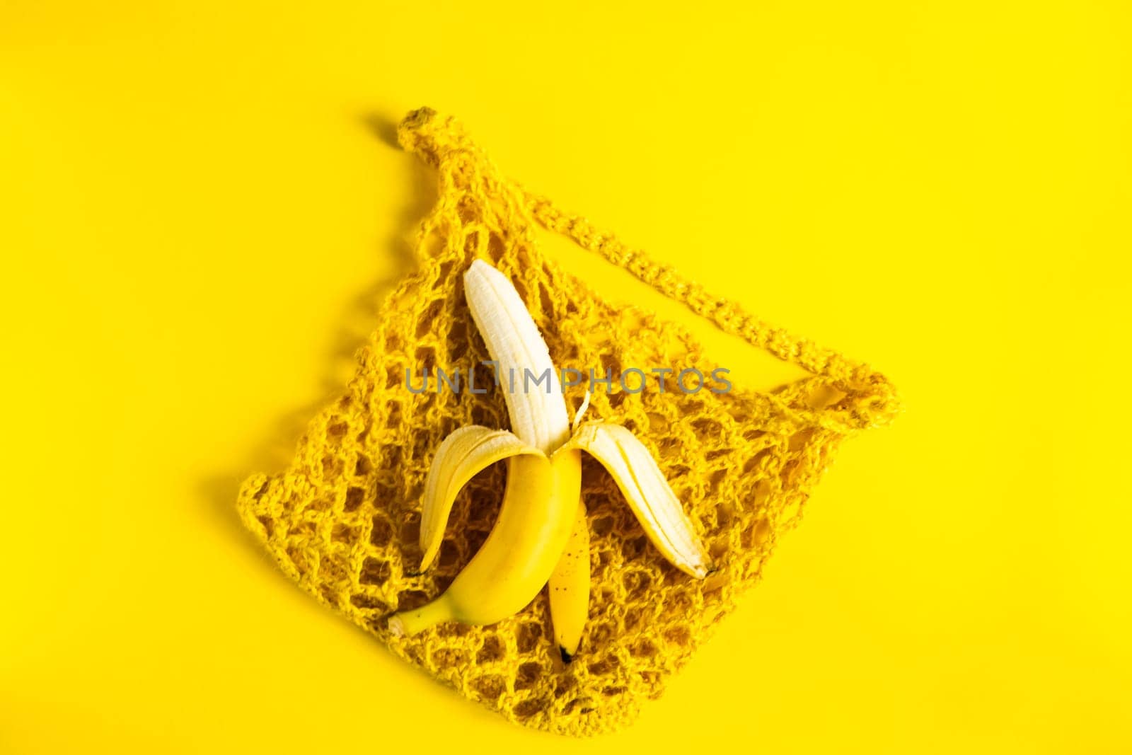 A string bag with bananas isolated on yellow background.