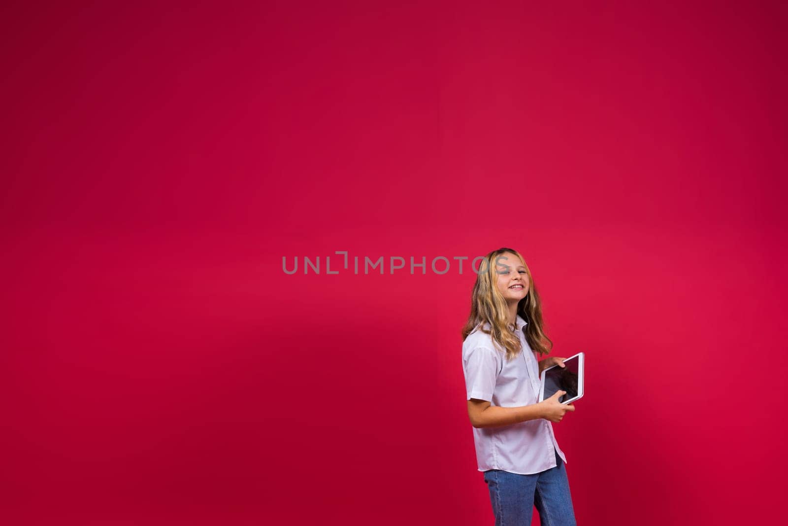 Online school app. Schoolgirl showing tablet computer Empty Screen On red Background. Studio Shot