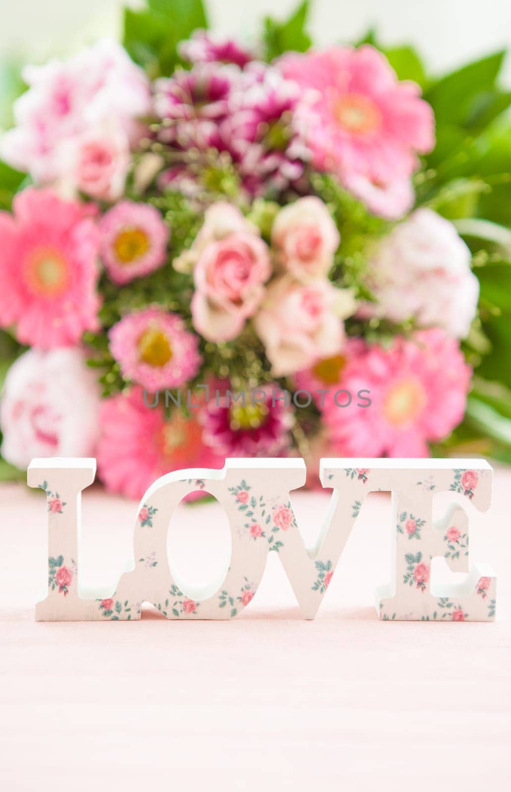 LOVE in front of colorful bouquet of flowers on pink