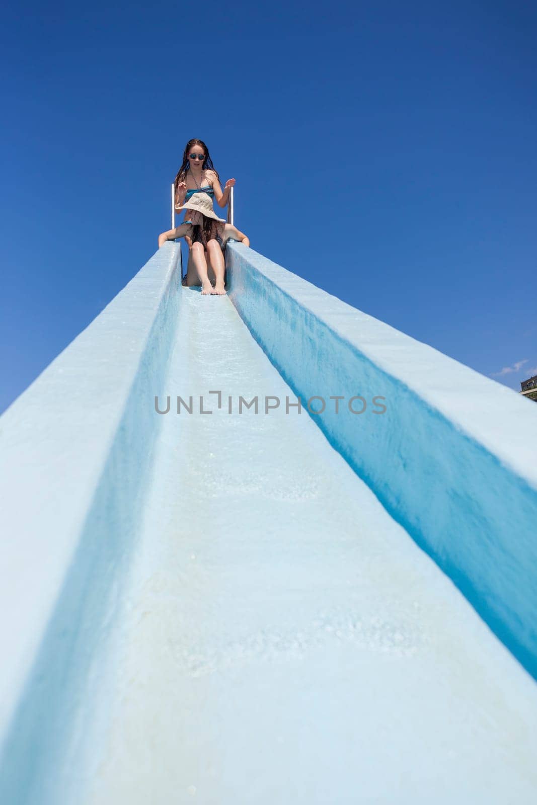 Girl teenager on swimming pool water slide summer fun.