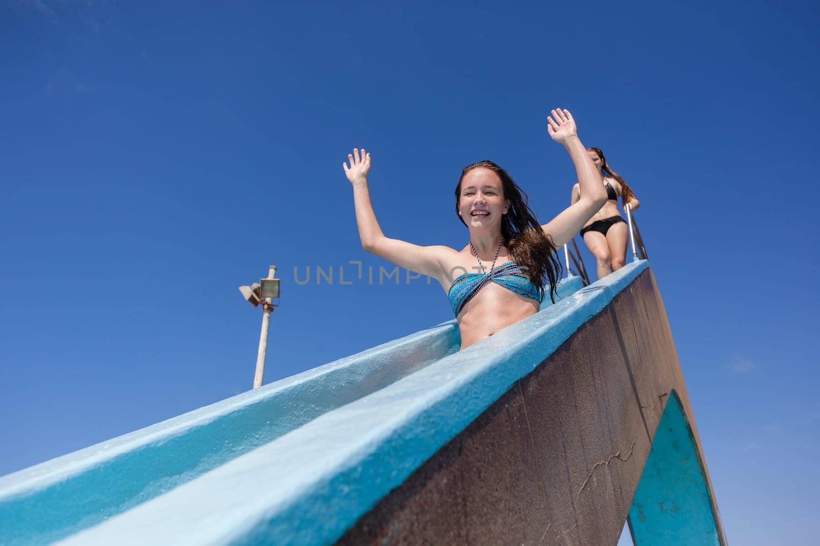 Girl teen on swimming pool water slide summer fun.