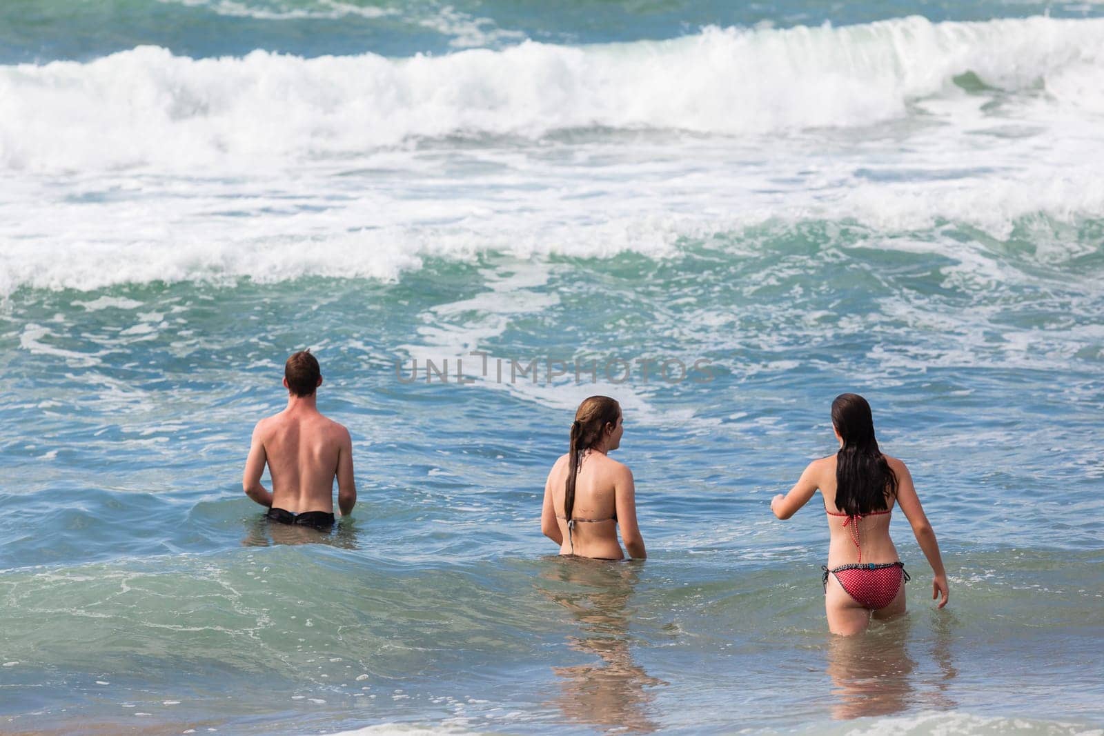 Boy Girls teenagers at beach swimming sea ocean shorebreak waves fun