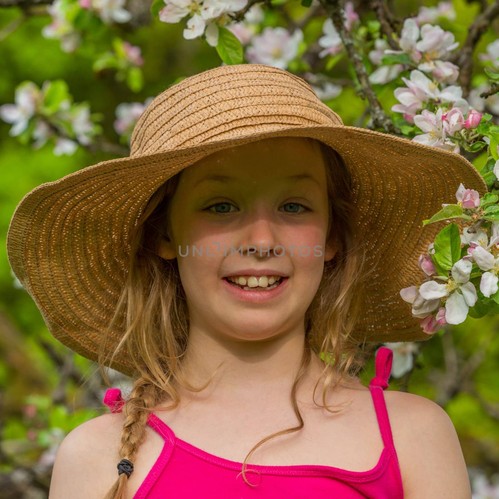 Portrait of a blonde girl in front of apple blossoms