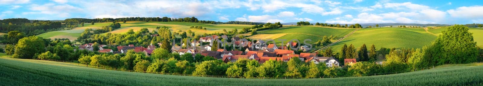Super wide panorama of a small German village surrounded by green landscaped hills