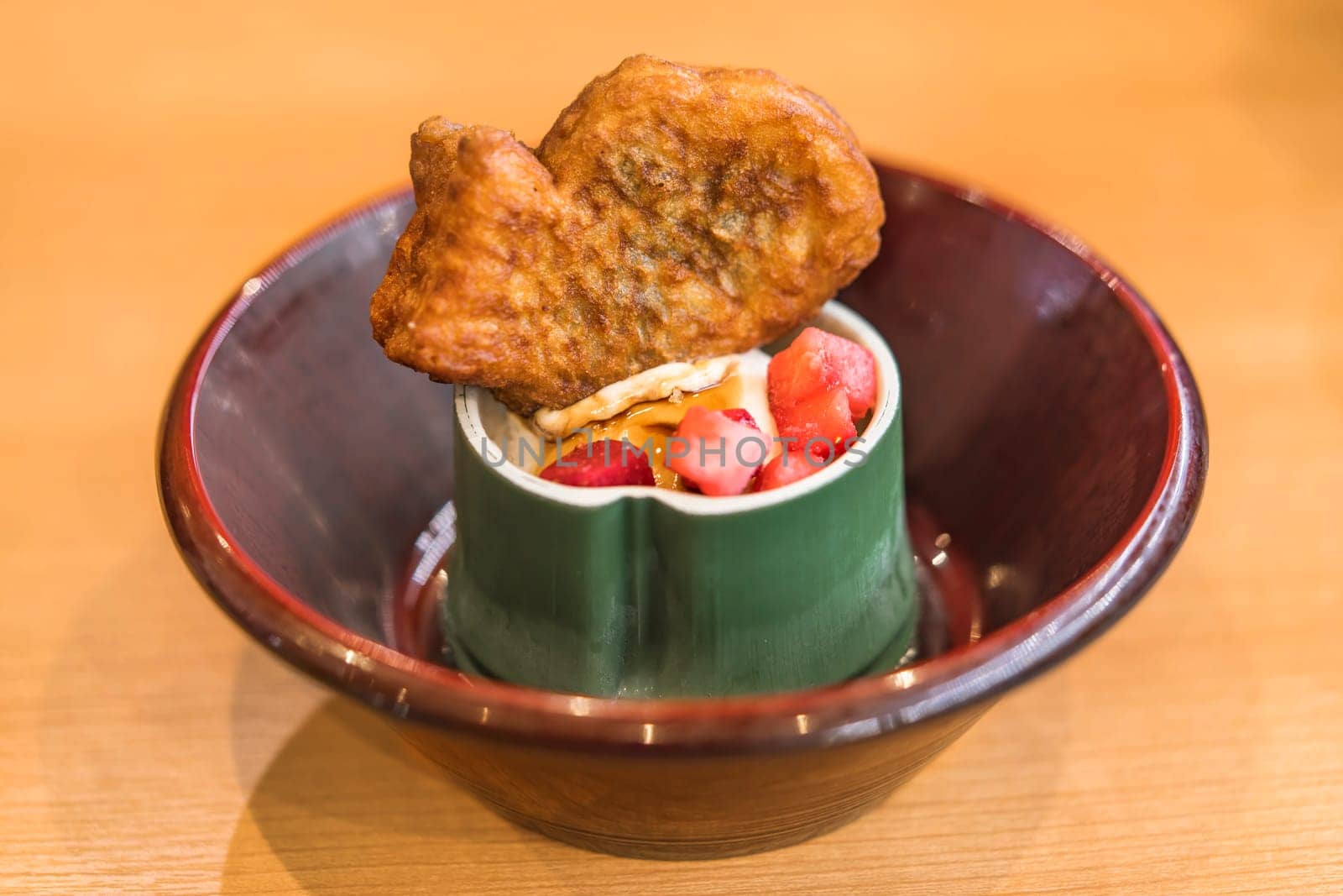 Japanese fish-shaped sweet Taiyaki with red beans or custard paste inside and strawberries on vanilla ice in a bamboo shaped cup.