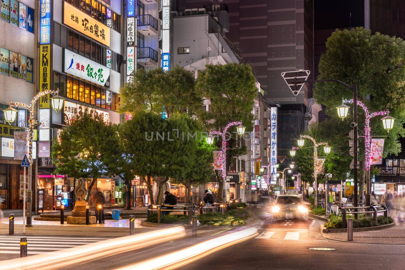 ikebukuro, japan - december 31 2022: Night view of the Sunshine Street at the east exit of Ikebukuro station illuminated by christmas illuminations and cars headlights.