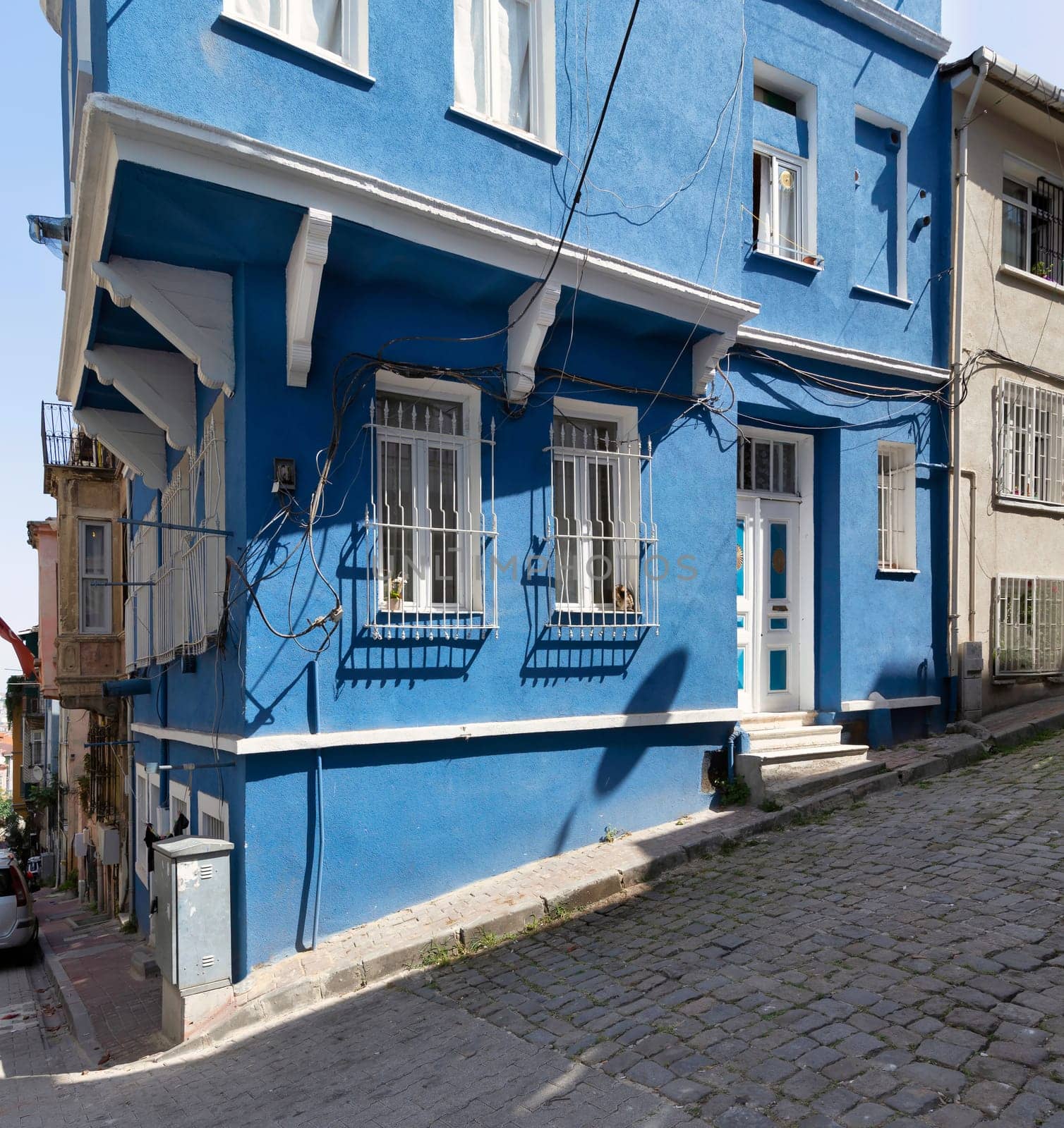 Cobblestone alley with beautiful old traditional blue painted house in old Balat district, on a summer day, Istanbul, Turkey