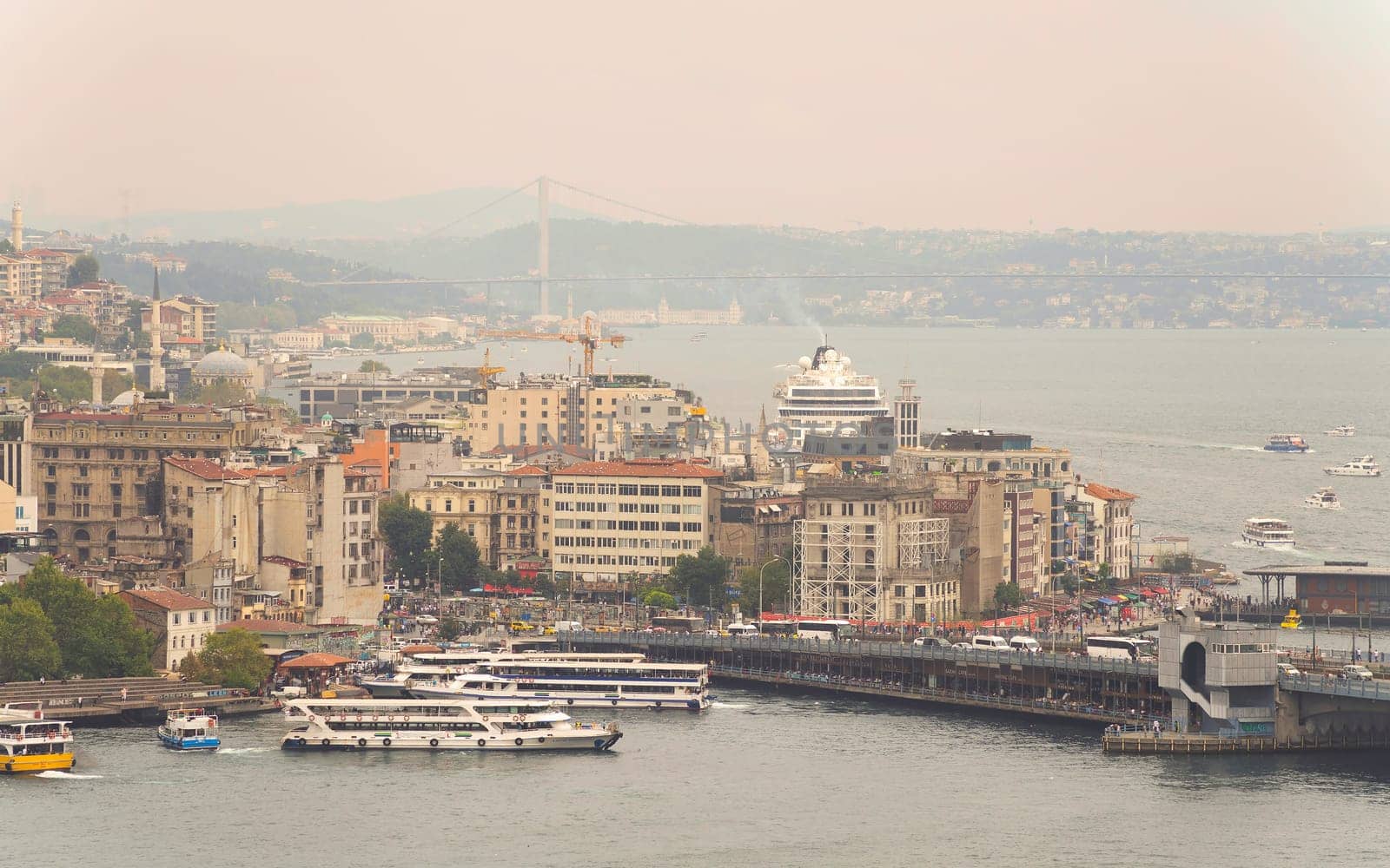 Aerial view of Golden Horn, with Galata Bridge and Karakoy Ferry Terminal with ferry boats approaching the terminal, and Bosphorus bridge in the far end, Istanbul, Turkey