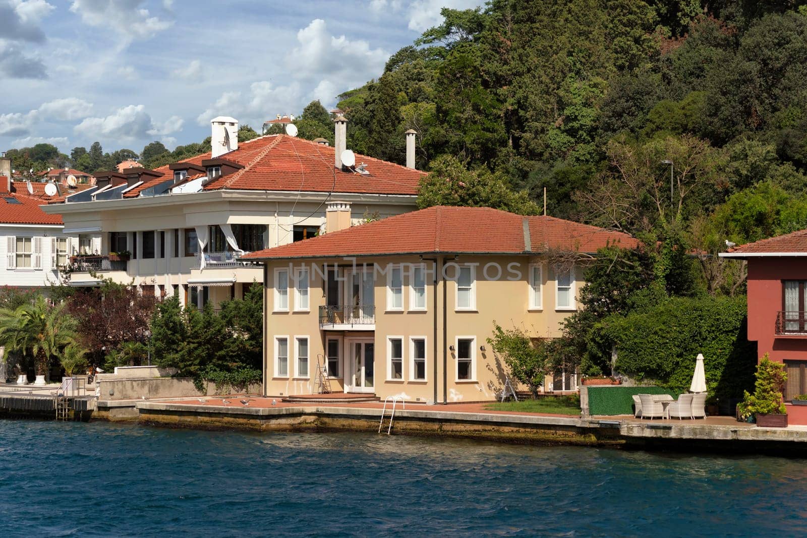 View from Bosphorus strait of the green mountains of the Asian side, with traditional houses and dense trees in a summer day, Istanbul, Turkey