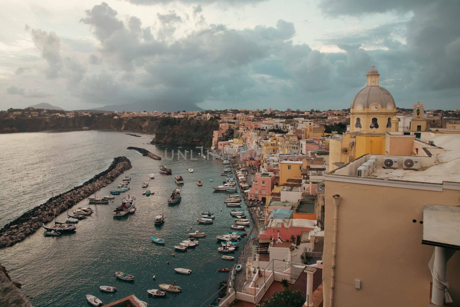View of the Port of Corricella with lots of colorful houses after sunset in Procida Island, Italy.