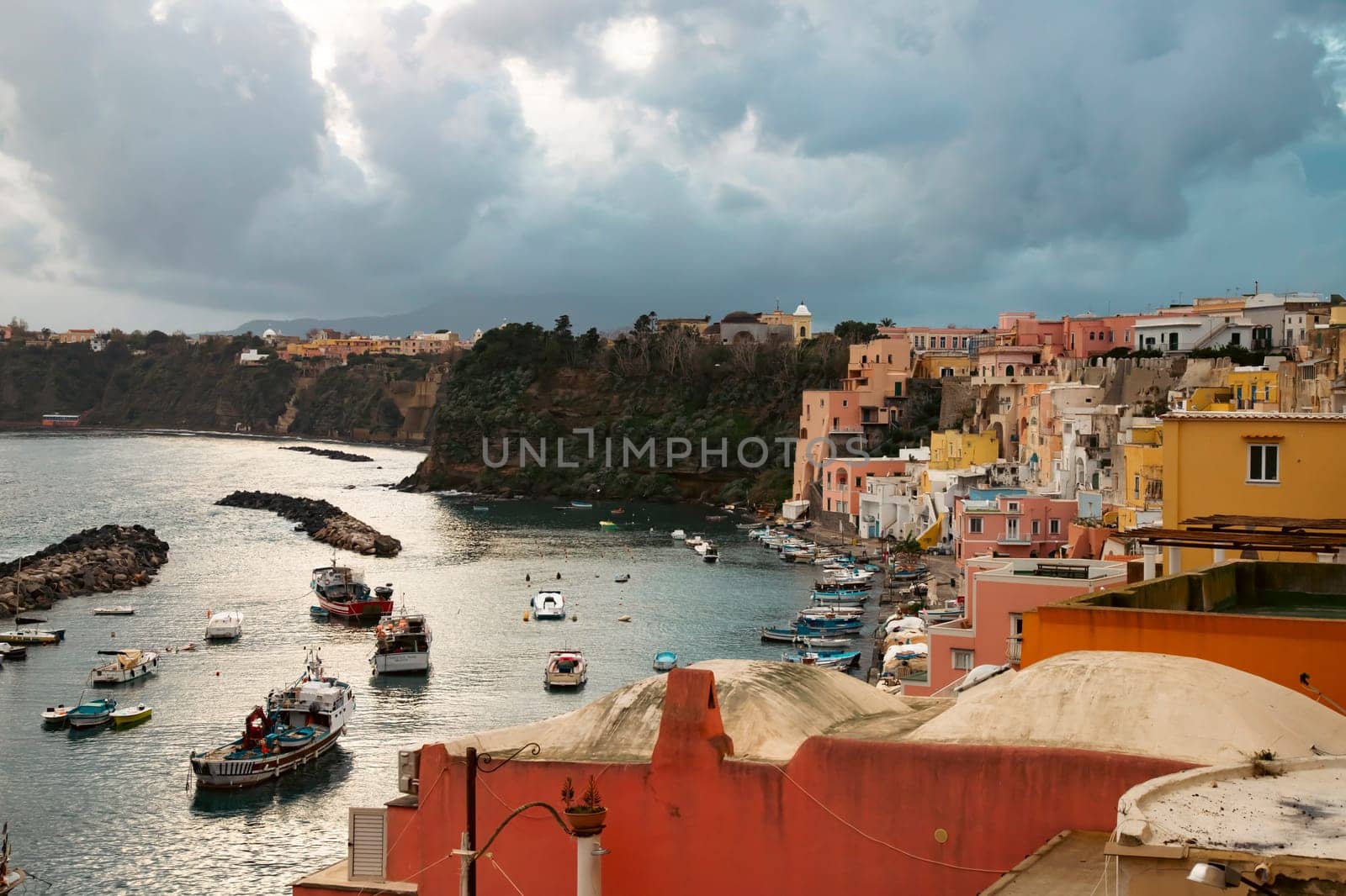 View of the Port of Corricella with lots of colorful houses on a sunny day in Procida Island, Italy.