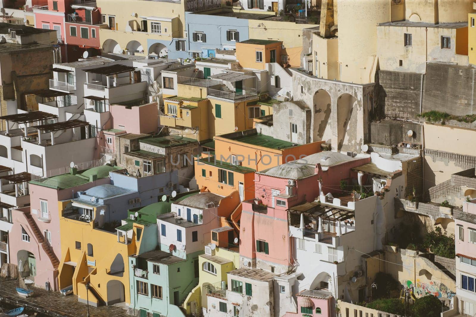 View of the Port of Corricella with lots of colorful houses on a sunny day in Procida Island, Italy.