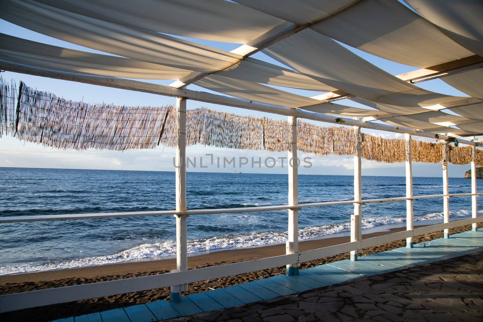 Cozy terrace on the beach, idyllic view of the seashore. Tropical summer vacation concept.