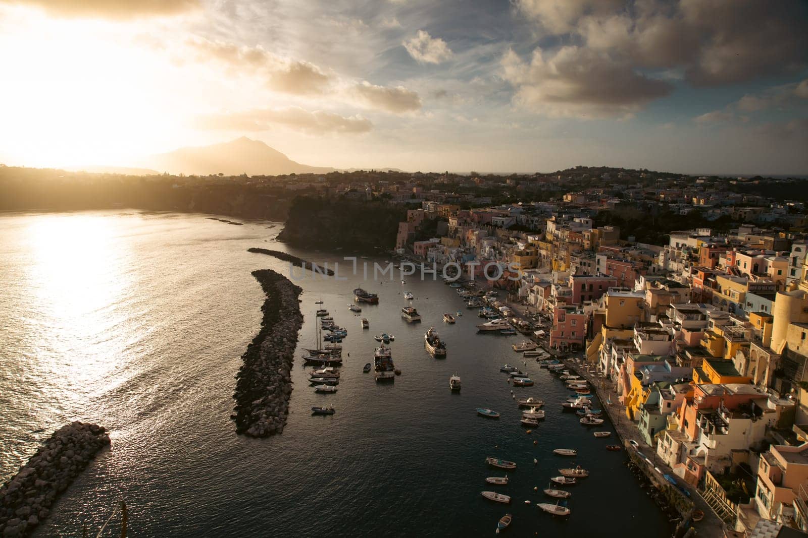 View of the Port of Corricella with lots of colorful houses in the sunset, Procida Island, Italy.