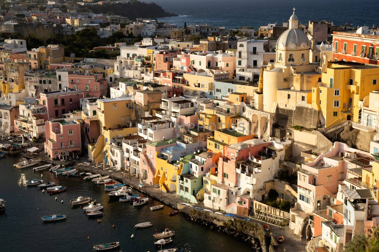 View of the Port of Corricella with lots of colorful houses in the sunset, Procida Island, Italy.